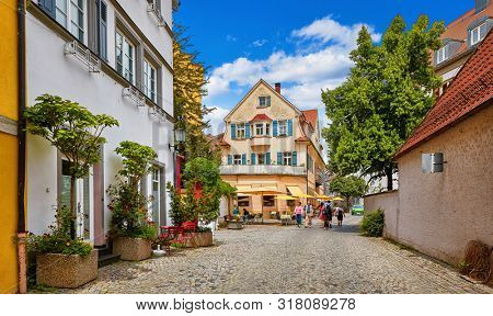 Cosy street in picturesque bavarian town Lindau at Lake Constance (Bodensee) in Germany. Traditional old german houses with cafe. Sunny summer day.