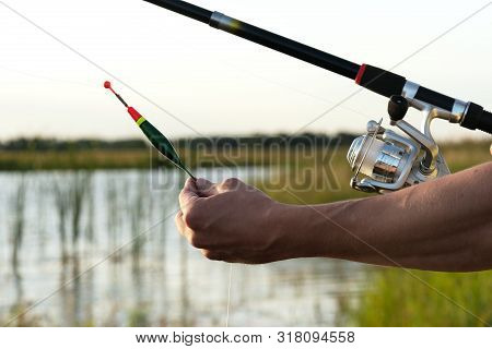 Fisherman With A Rod In Hands Is Adjusting The Depth By Fishing Float.