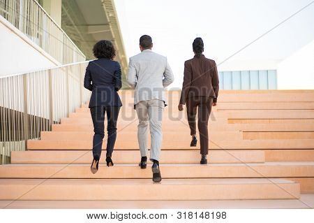 Businesspeople Walking Near Office Building. Rear View Of Business Man And Women Going Upstairs Toge