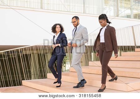 Serious Business Colleagues Walking To Their Office Together. Three Business Man And Women Going Dow