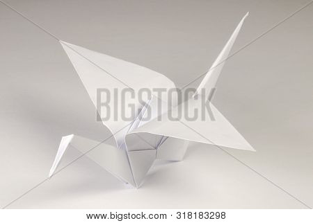 Light Gray Origami Crane On Gray Background. Tsuru. Japanese Art Of Paper Folding. Flat Square Sheet