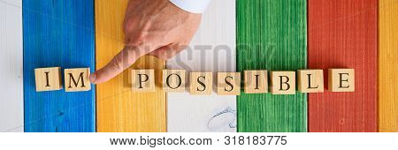 Wide View Image Of Male Finger Pushing Away Letters Im From The Word Impossible Spelled With Wooden 