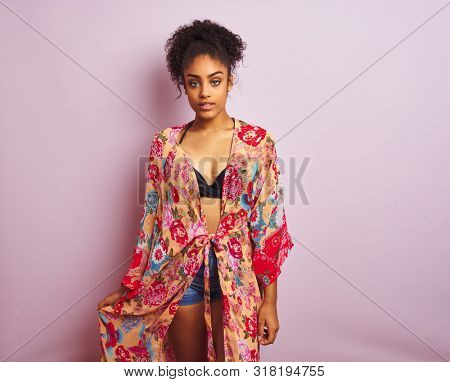 Young beautiful african american woman on vacation standing wearing bikini and colorful caftan