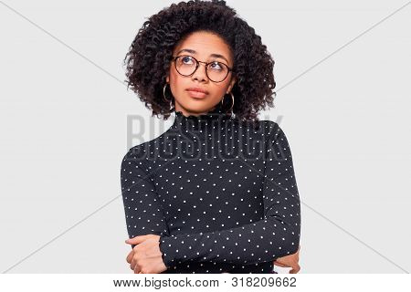 Serious African American Young Woman, Wears Casual Outfit And Transparent Eyeglasses. Afro Female In
