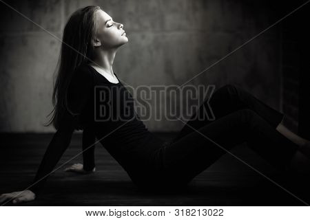 A full length portrait of a thoughtful young woman posing on the floor. Beauty, fashion.