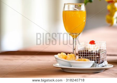 Orange Juice In Champagne Glass With Cake And Bagery Beside.