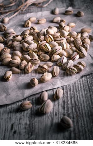 Pistachios On Wooden Table In The Foreground With Darkened Background