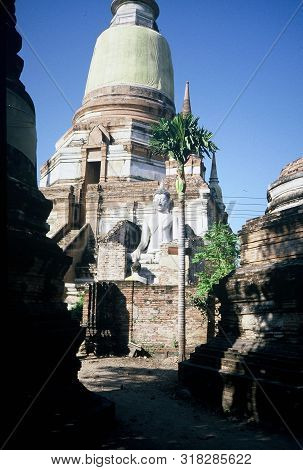 An Image Of The Meditating Buddha Sits Serenely In Front Of The Ruins Of A Chedi At Wat Yai Chai Mon