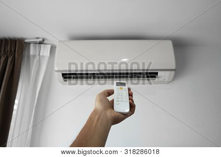 Mans Hand Using Remote Controler. Hand Holding Rc And Adjusting Temperature Of Air Conditioner Mount