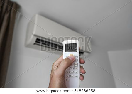 Mans Hand Using Remote Controler. Hand Holding Rc And Adjusting Temperature Of Air Conditioner Mount