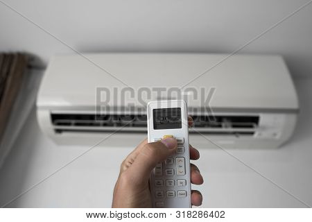 Mans Hand Using Remote Controler. Hand Holding Rc And Adjusting Temperature Of Air Conditioner Mount
