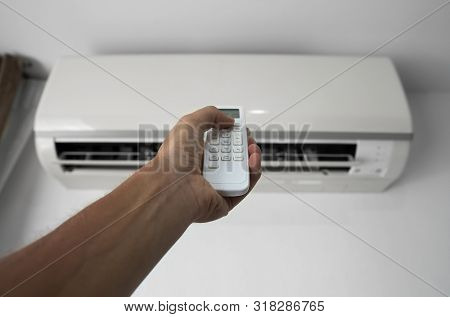 Mans Hand Using Remote Controler. Hand Holding Rc And Adjusting Temperature Of Air Conditioner Mount
