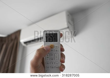 Mans Hand Using Remote Controler. Hand Holding Rc And Adjusting Temperature Of Air Conditioner Mount