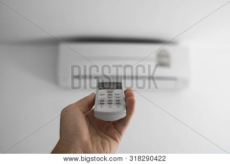 Mans Hand Using Remote Controler. Hand Holding Rc And Adjusting Temperature Of Air Conditioner Mount