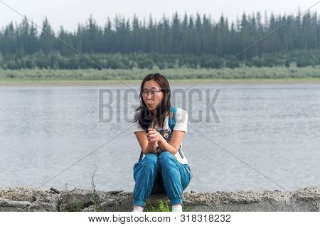 Surprised Sports Yakut Asian Girl With Glasses Young Girl Sitting On The Old Pier Of The Vilyui Rive