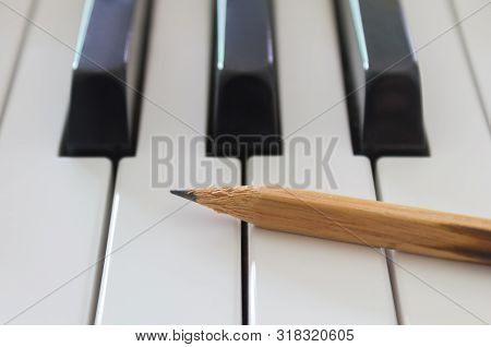 Old Pencil On White Keys Of Electric Piano In Crosswise View. Concept About Piano Playing Or Piano L