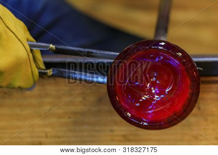 Glass Blower Shaping A Bubble Of Melted Glass On A Rod By Hand In The Manufacturing Process At A Gla