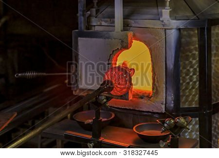 Glass Blower Manufacturing Process, Working On A Bubble Of Melted Glass On A Rod By Heating It Up By