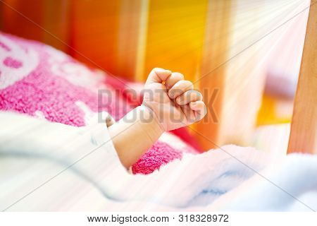 Hand Of An Energetic Newborn Baby With Light Blue And Pink Blanket And Baby Bed. Close Up.