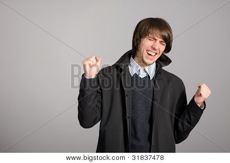expressive junger Mann auf einem Hintergrund von grauen Wänden.