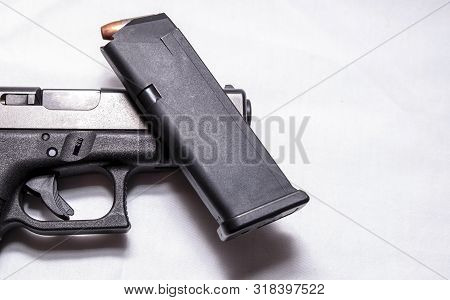 A Loaded 9mm Pistol Magazine On Top Of A Black 9mm Pistol On A White Background