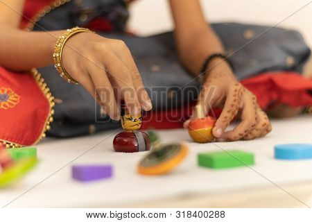 Focus On Hands Of Cute Little Child Girl Playing With Indian Wooden Channapatna Toys In The Room