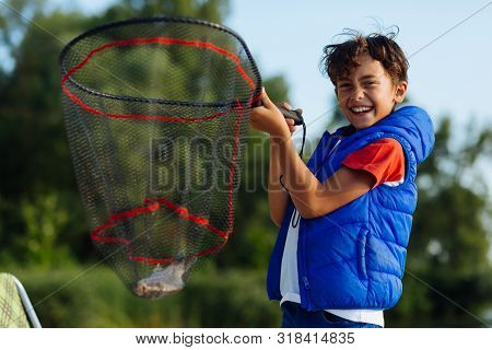 Handsome Boy Smiling After Catching Fish Into Net