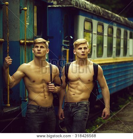 Handsome Young Guys With Muscular Body Standing Shirtless In Pants With Beautiful Torso Near Blue Ol