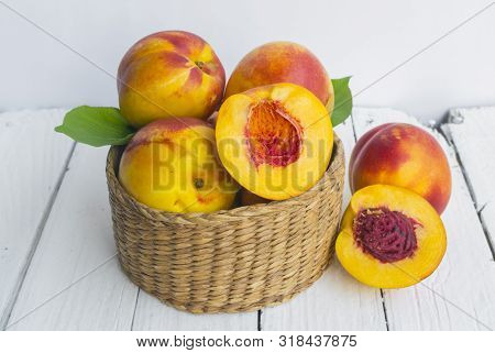 Delicious And Juicy Peach (nectarina) In Basket  On White Wooden Table With Place For Text