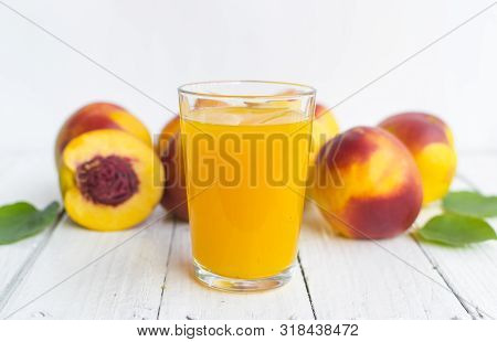 Delicious And Juicy Peach (nectarina) With Glass Of Juice On White Wooden Table.