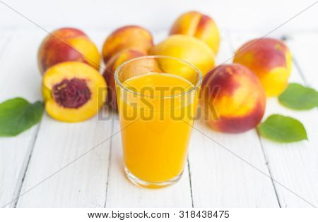 Delicious And Juicy Peach (nectarina) With Glass Of Juice On White Wooden Table.