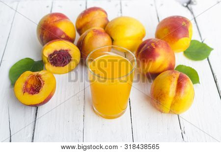 Delicious And Juicy Peach (nectarina) With Glass Of Juice On White Wooden Table.