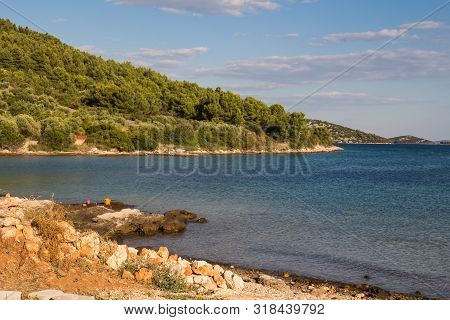 Empty Beach With Rocky Coast. Blue Clean Water Of The Adriatic Sea With Small Waves. Hill With A For