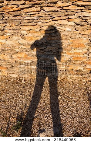 Wall Outdoors, Made Of Split Natural Stones. Silhouette Of A Woman (author), Long Hair And Legs. Tis