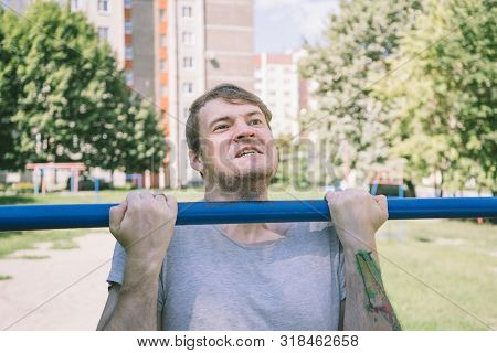A Young Handsome Man In Casual Clothes Is Doing Pull Up Exercise On Horizontal Bar. Fitness, Sport, 