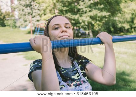 A Young Handsome Woman In Casual Clothes Is Doing Pull Up Exercise On Horizontal Bar. Fitness, Sport