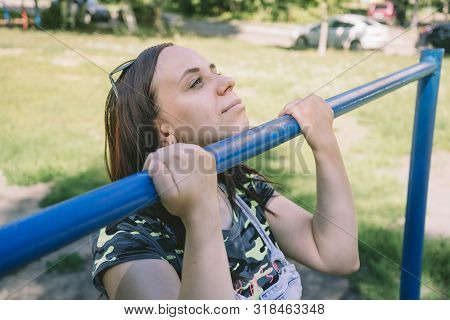 A Young Handsome Woman In Casual Clothes Is Doing Pull Up Exercise On Horizontal Bar. Fitness, Sport