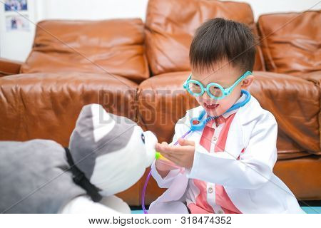 Cute Smiling Little Asian 3 - 4 Years Old Toddler Boy In Doctor Uniform Playing Doctor With Plush To