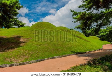 Four Songsan-ri Tombs In Gongju Under Beautiful Blue Sky With Large White Puffy Clouds.