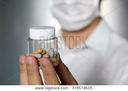 Doctor Giving Pills, Physician In Medical Mask Holding In Hands Bottle With Capsules. Concept Of Dos