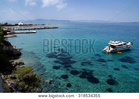 Greece, The Island Of Angistri, Near Athens.  Crystal Clear Water. Rocky Pine Covered Cliffs.  A Sun