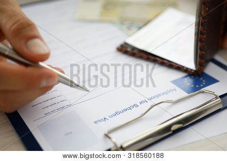 Male Hand Hold Silver Pen With Passport. Filling Schengen Apllication Form Concept