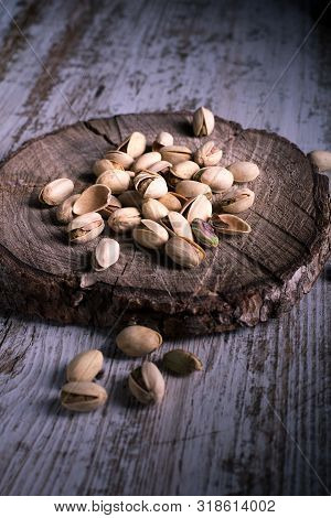 Pistachios On Wooden Table In The Foreground With Darkened Background