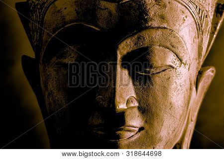 Buddhism. High Contrast Buddha Face Close-up With Dramatic Side Light. Metallic Stone Statue With Ca