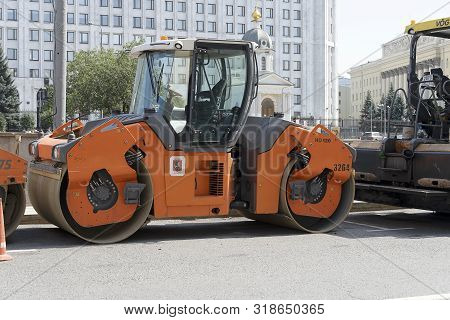 Russia, Moscow, 2019-08-10. An Orange Road Roller Stands Near The Road. Preparation For Repair Of Th