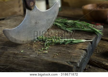 Sharp Knife And Rosemary On A Rutic Wooden Board