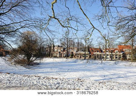 Frozen Water And Show On Canal And Traditional Old Brick Buildings With Tile Roofs At Sunny Winter D