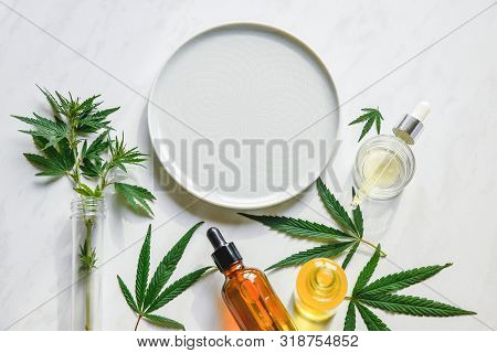 Various Glass Bottles With Cbd Oil, Thc Tincture And Hemp Leaves On A Marble Background. Copy Space,