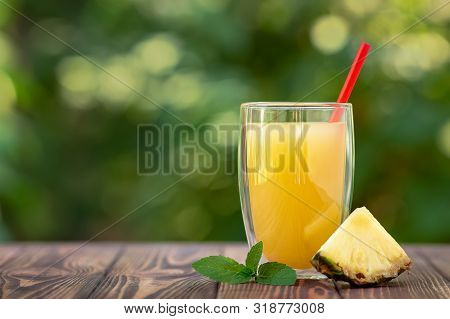 Fresh Pineapple Juice In Double Sided Wall Glass On Wooden Table Outdoors. Summer Refreshing Drink