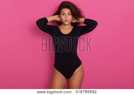 Beautiful Young And Stylish Woman Wearing Black Kombidress, Keeps Hands On Head, Looking At Camera W